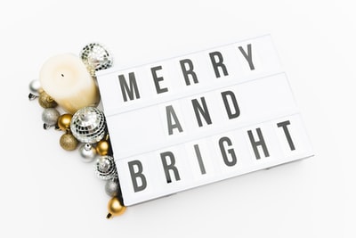 蜡烛旁边的银色和金色小玩意和带有 Merry and Bright 印花的标牌
